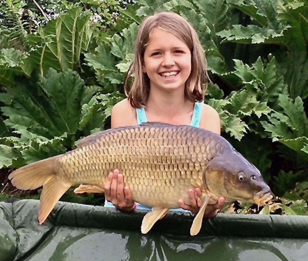 happy young angler in the UK displays a healthy common carp she has just landed.