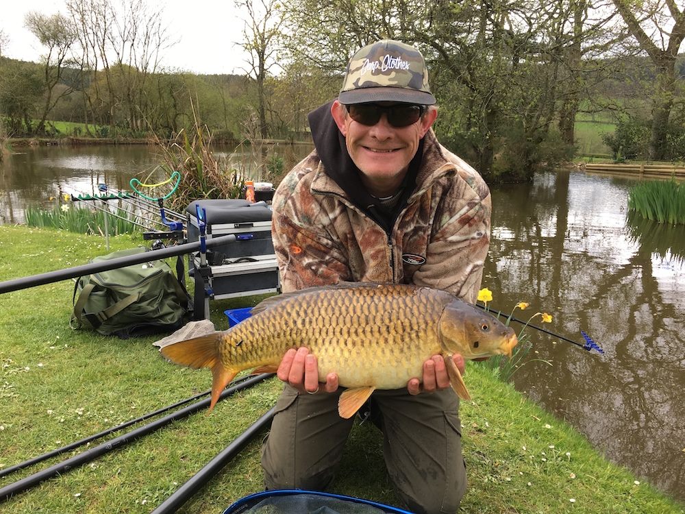 An angler beams while holding a good-sized common carp he has caught at South Farm Holiday Cottages & Fishery